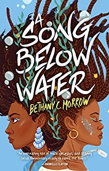 Cover of A Song Below Water, by Bethany C. Morrow. Two teenage girls stand back to back, close enough to lean against each other. Their long hair, in twists and coils, floats upward -- the background is light blue, with a few bubbles floating up with the girls' hair. The girl on the left has light blue eyeshadow and a light blue earring that looks like a chandelier. The girl on the right also has blue eyeshadow, with a small gold hoop earring and a streak of blue scales and glitter on her cheek. Both girls have light gray-green seaweed woven into their hair.